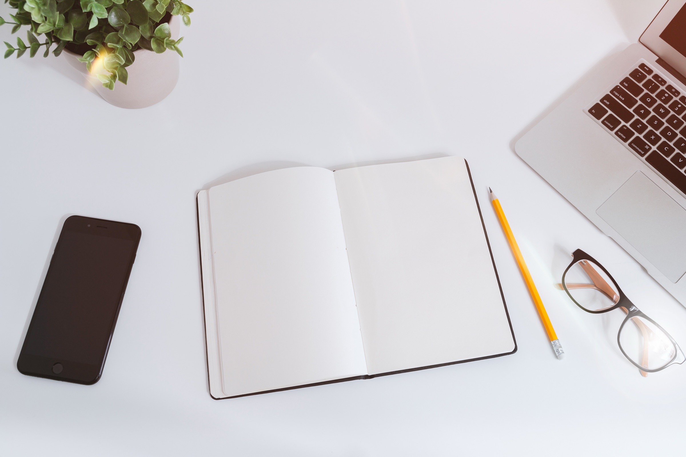 Open notebook, laptop and phone on a desk for planning support workflows